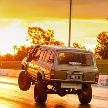 Bushdoof window banner sticker across the rear glass of a lifted 60 Series LandCruiser at the drag strip