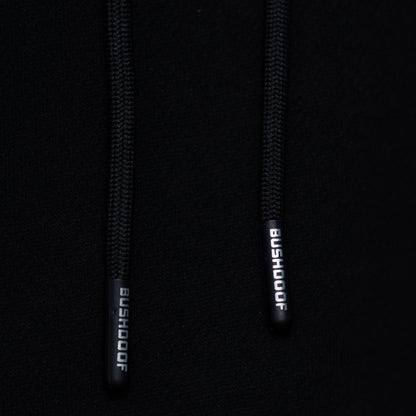 Bushdoof Staple Hoodie in black, worn outdoors