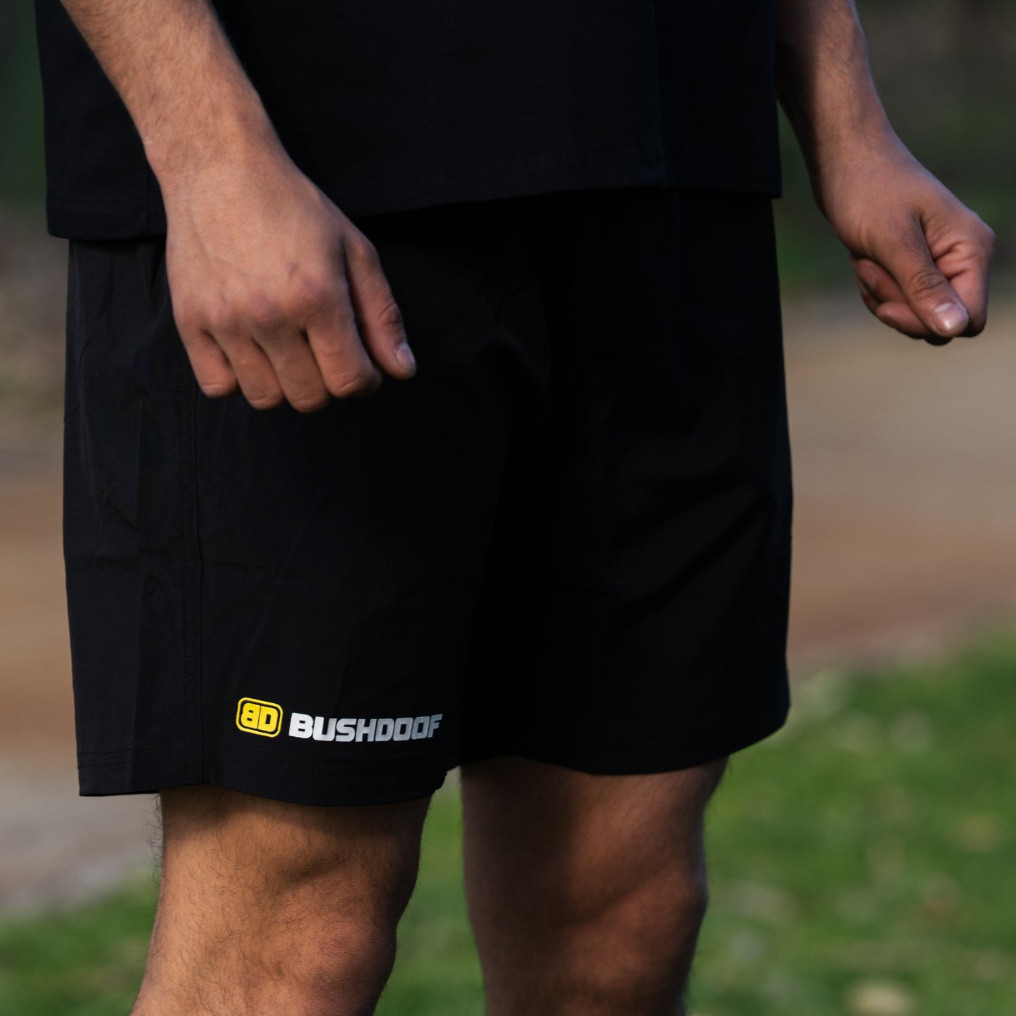 Bushdoof Staple Shorts in black, worn outdoors