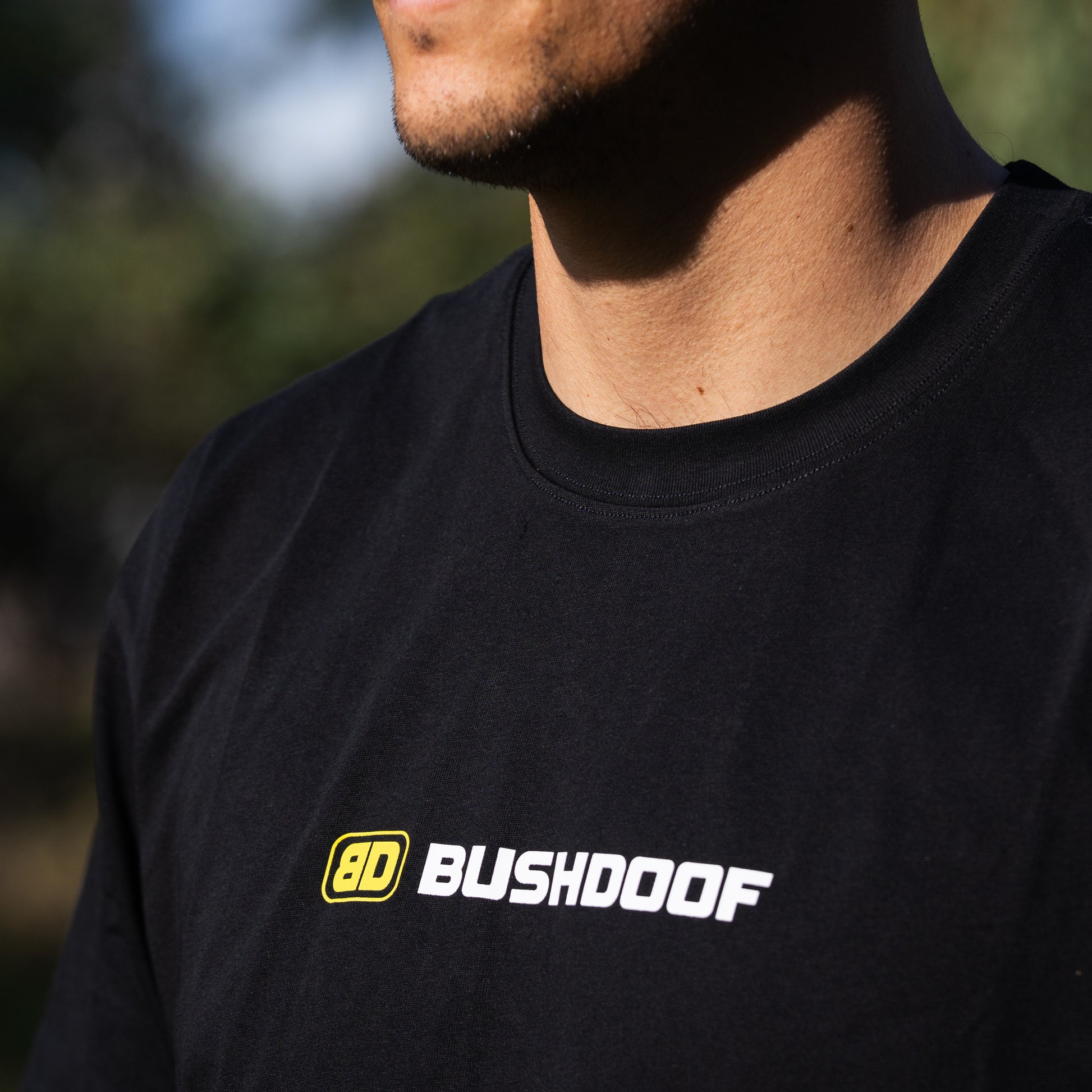 Bushdoof Staple Tee in black, worn outdoors
